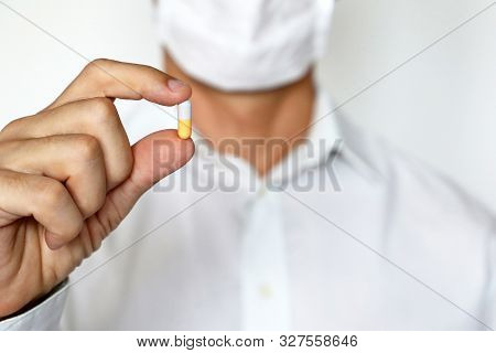 Doctor In Medical Mask Holding Pill, Male Hand With Medication In Capsule Close-up. Man With Tablet,