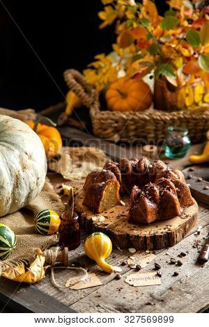 Tasty Homemade Baked Pumpkin Bundt Cake With Chocolate On Top Stands On Wooden Board On Rustic Table