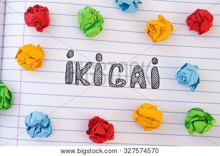 The Word Ikigai On Notebook Sheet With Some Colorful Crumpled Paper Balls Around It. Ikigai Is A Jap