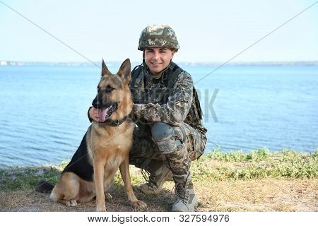 Man In Military Uniform With German Shepherd Dog Near River