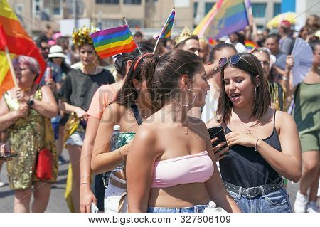 Gay And Lesbians Walking In The Gay Pride Parade. Parade Of Tolerance. Rainbow Flags At Gay Pride Pa