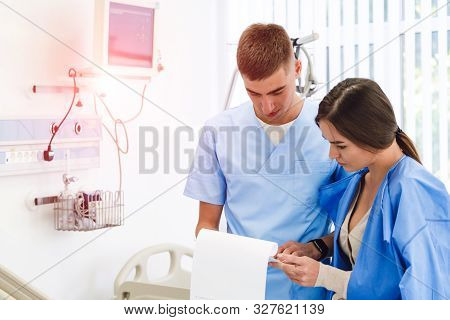 Doctor Physician Consulting With Female Patient In Hospital Exam Room. Checking Medical Results. Med