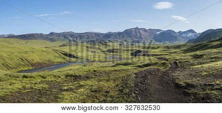 Panoramic Landscape With Blue River Stream, Green Hills, Snow-capped Mountains, Meadow And Lush Moss