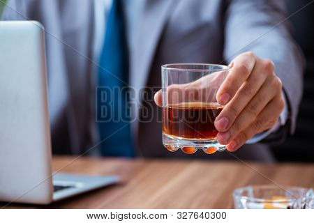 Male employee drinking alcohol and smoking cigarettes at workpla