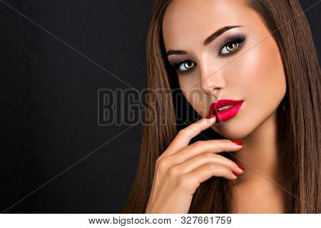 Closeup portrait of beautiful seductive woman with dark brown eye makeup and bright red lips and nails