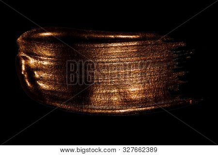 Creative brushstrokes of gold paint isolated on a black background. Gold paint texture.Acrylic gold paint. Smears of cosmetics, blush, highlighter, eye shadow, lipstick.