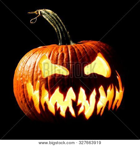 Halloween carved Jack o lantern pumpkin glowing eerily in the dark