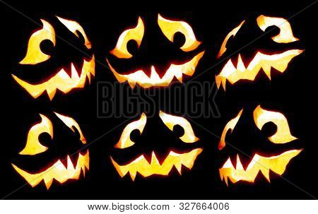 Collection of scary Halloween pumpkin Jack o lantern faces glowing red and yellow eerily on black