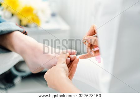 Podiatrist cutting nails on feet of man during pedicure with scissors