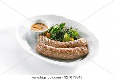 Macro shot of Munich sausages for frying made from pork and beef with mustard sauce and mixed salad isolated. Traditional German rostbratwurst, wurst or bratwurst with vegetables and greens closeup