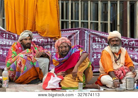 PURI, INDIA, JANUARY 13, 2019 : Three Indian yogis in traditional clothes are sitting in the street of the large market near the Shree Jagannath Temple