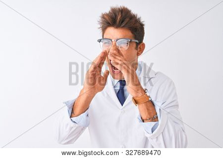 Young handsome sciencist man wearing glasses and coat over isolated white background Shouting angry out loud with hands over mouth