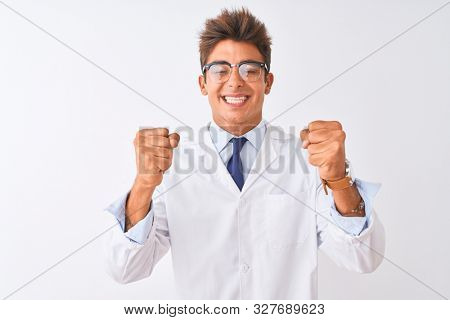 Young handsome sciencist man wearing glasses and coat over isolated white background excited for success with arms raised and eyes closed celebrating victory smiling. Winner concept.