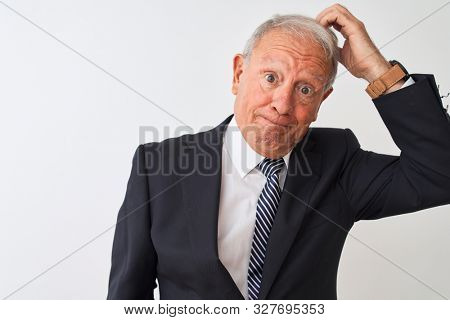 Senior grey-haired businessman wearing suit standing over isolated white background confuse and wonder about question. Uncertain with doubt, thinking with hand on head. Pensive concept.