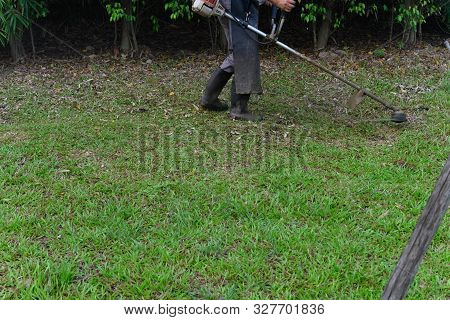 Worker Operating A Handheld Lawn Mower And Cutting Grass