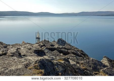 Sailing Boat On The Calm Lake Turgoyak, View From The Rocky Shore In Autumn, Southern Urals