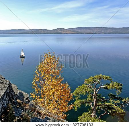 Sailing Boat On The Calm Lake Turgoyak, View From The Rocky Shore In Autumn, Southern Urals, The Lak