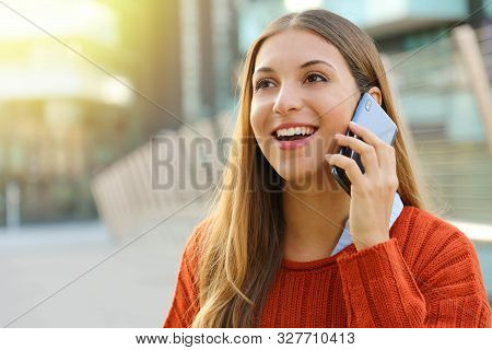 Pretty Cheerful Young Woman Talking On Phone And Looks Straight Ahead. Girl Holding Smartphone Close