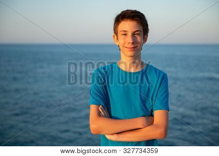 Handsome young boy at beach. Beautiful calm smiling teen boy at Mediterranean sea coast. Travel, summer vacation, tourism, teenage lifestyle.