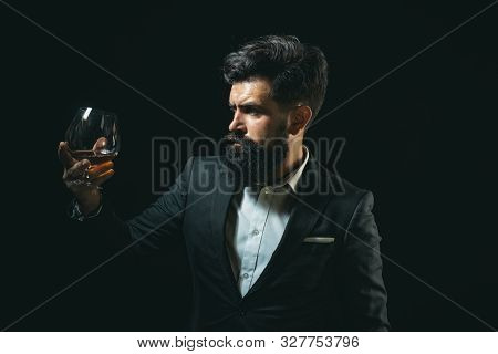 Drinking Whiskey Or Brandy Or Cognac. Elegant And Stylish Man In Classical Wear Holding Glass With W
