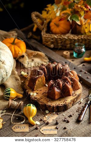 Tasty Homemade Baked Pumpkin Bundt Cake With Chocolate On Top Stands On Wooden Board On Rustic Table