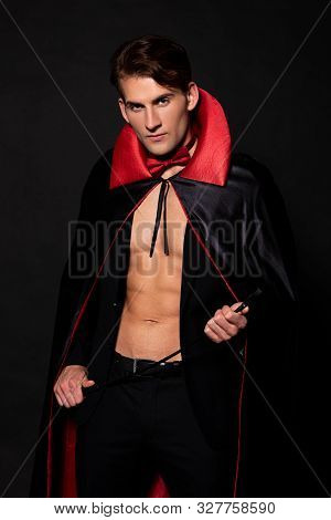 Man In Vampire Halloween Costume Holding Flogging Whip Isolated On Black