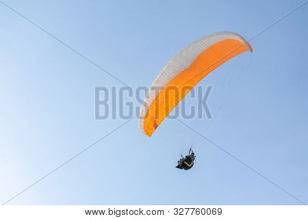 Togliatti, Russia - 10 March 2019. Paragliding On The Background Of Blue Sky. The Orange Paraglider 
