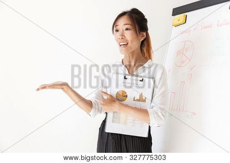 Attractive confident asian businesswoman presenting new project at the blankboard isolated over white background