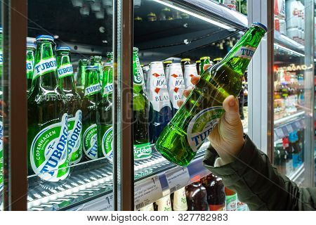 Minsk, Belarus - October 4, 2019: Buyer Takes Tuborg Beer In Refrigerator Of Supermarket. Hand Is Ho