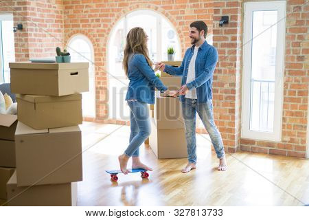 Young couple moving to a new home, having fun riding a skateboar