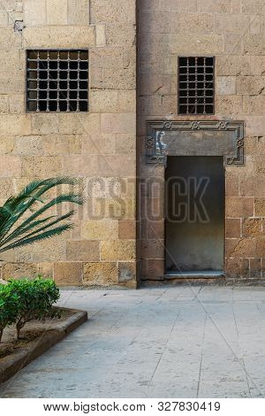 Ancient External Old Decorated Bricks Stone Wall With Two Windows And Opened Door Leading To Ottoman