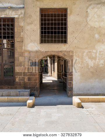 Ancient External Old Decorated Bricks Stone Wall With Two Windows And Arched Passage Entrance Leadin