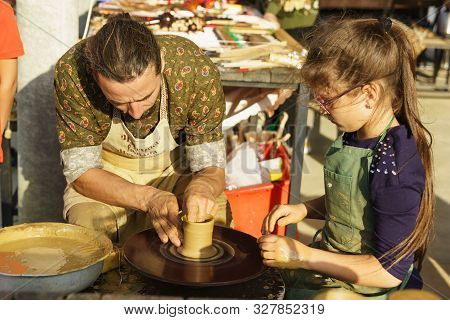 Moldavanskoye, Krymsk, Russia-05 October 2019: A Potter Teaches A Girl How To Make A Jug Of Yellow C