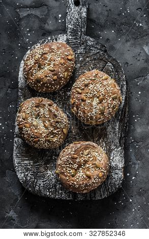 Multigrain Multiseed Fitness Buns On Rustic Wooden Chopping Board On Dark Background, Top View