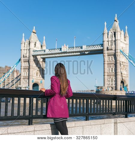 London people lifestyle city tourist woman looking at view of Tower Bridge in red trench coat. Bridge. Stylish elegant lady fashion girl walking enjoying urban modern life.