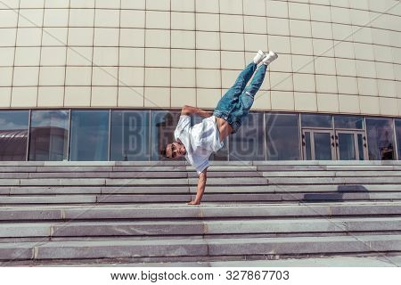 Acrobat Dancer Stands On One Arm, Dancing Break Dance, Hip-hop. Summer City, Background Building. Ac