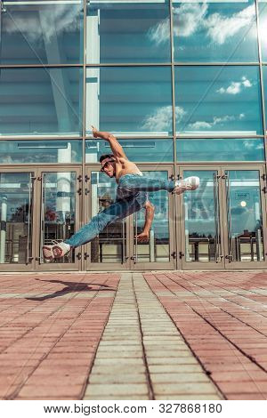 Jumping Dancer, Acrobat Actor Break Dance, Hip Hop. In Summer City, Background Is Glass Windows Clou