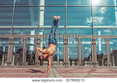 Dancer In Jump Stands On One Arm, Acrobat Actor Break Dance, Hip-hop. In Summer City, Background Gla