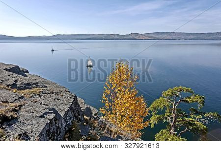 Sailing Boat On The Calm Lake Turgoyak, View From The Rocky Shore In Autumn, Southern Urals, The Lak