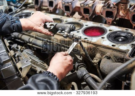 diesel truck engine repair service. Automobile mechanic tightening using wrench