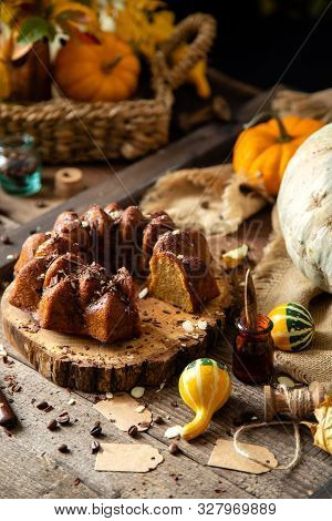Tasty Homemade Baked Pumpkin Bundt Cake With Chocolate On Top Stands On Wooden Board On Rustic Table