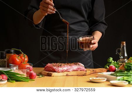 Chef Cooks Pork Steak. Pouring Sauce, Marinade On A Background W