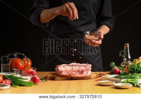 Chef Cooks Pork Ribs. Sprinkling With Salt On A Background With