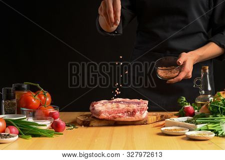 Chef Cooks Pork Ribs. Sprinkling With Salt On A Background With