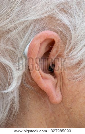 Hearing Aid. Female Pensioner With White Hair Wearing A Behind The Ear, Bte, Hearing Aid. Close Up O