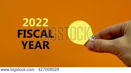 2022 Fiscal New Year Symbol. Businessman Holds Yellow Shining Light Bulb. Words '2022 Fiscal Year', 