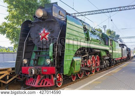 Green Retro Steam Locomotive At The Railway Station On A Sunny Day