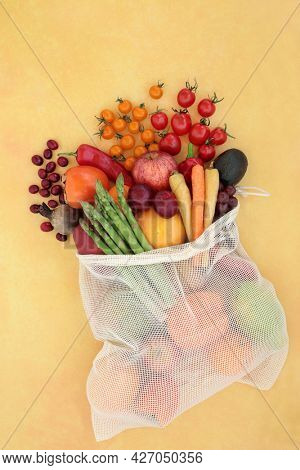 Healthy fruit and vegetables in a net shopping bag high in lycopene for a healthy heart and to lower blood pressure, high in antioxidants, anthocyanins, vitamins, minerals and dietary fibre. Top view