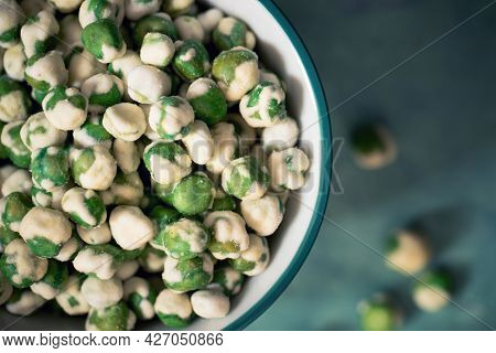 A closeup of wasabi peas, a spicy Japanese savory snack of dried green peas with a wasabi horseradish coating.