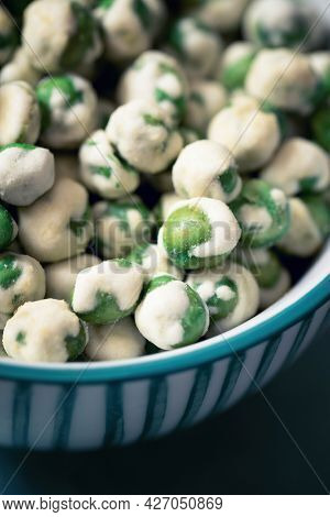 A closeup of a bowl of wasabi peas, a spicy Japanese savory snack of dried green peas with a wasabi horseradish coating.